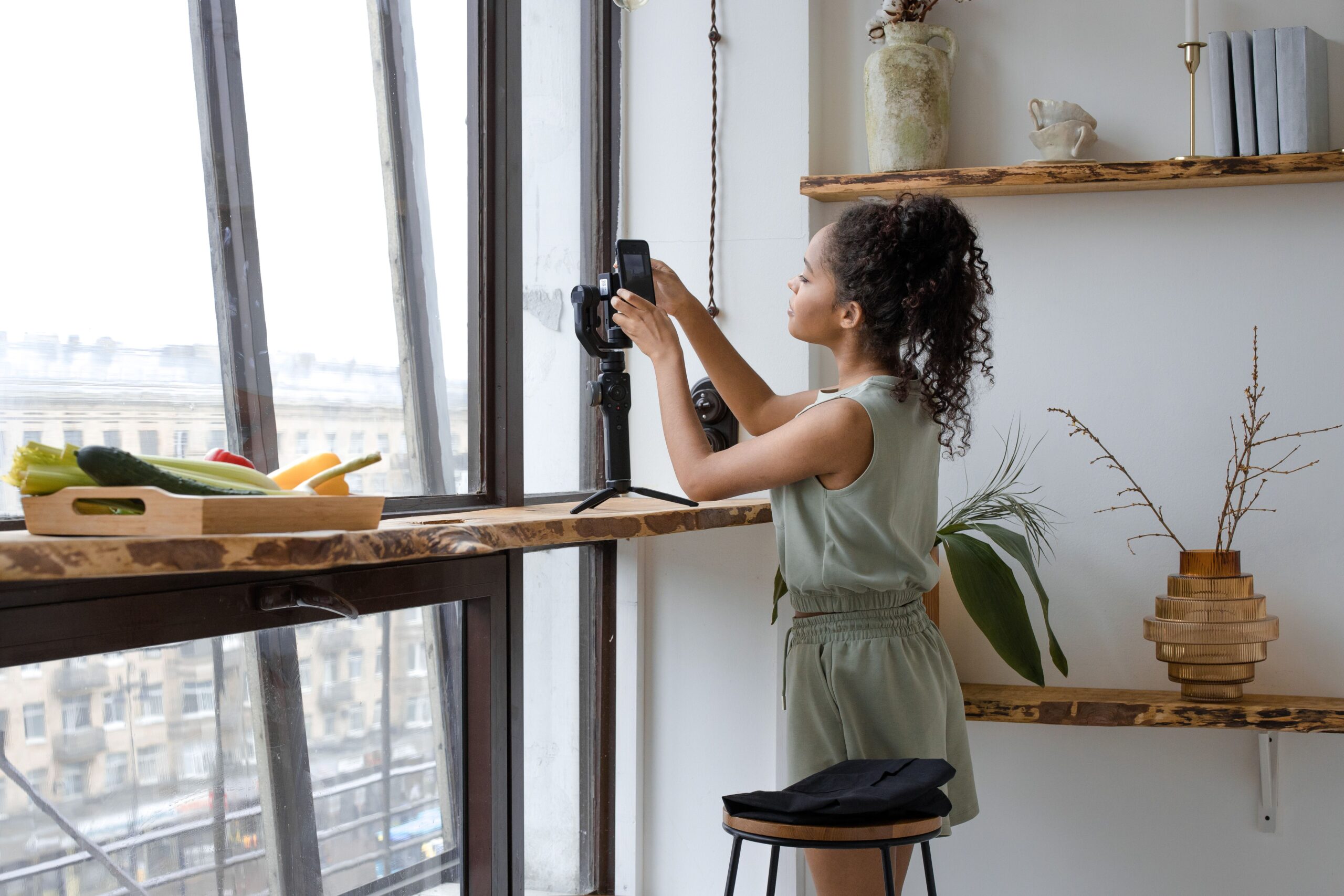 Creator filming content with a phone on a tripod by a window
